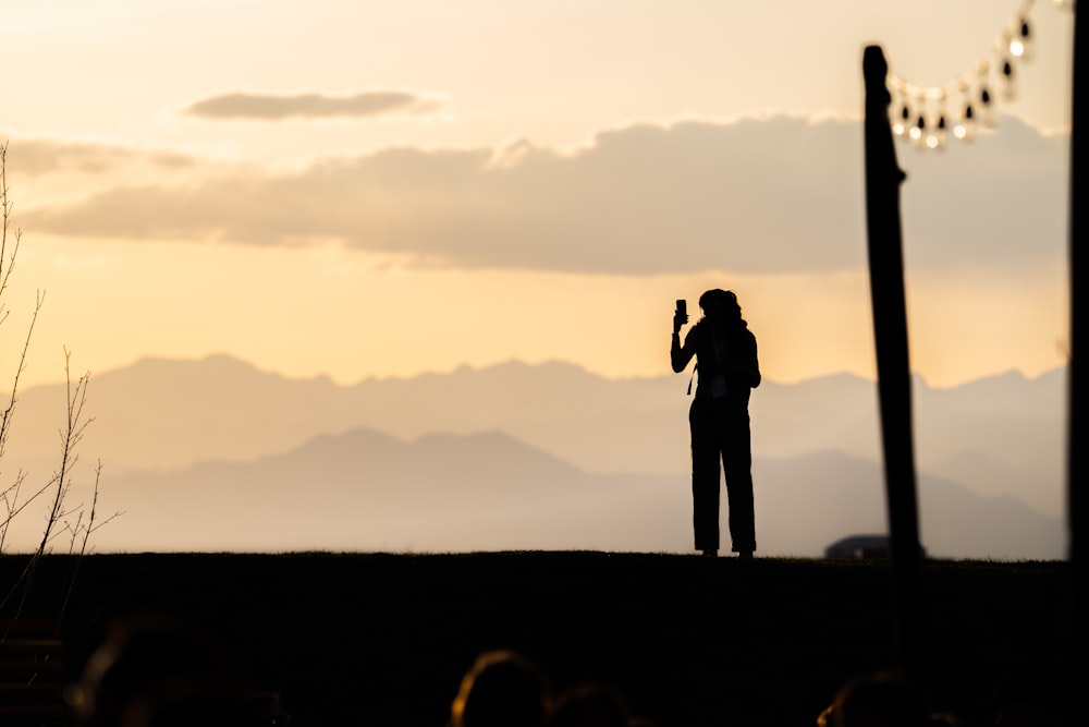 a woman standing on top of a hill holding a cell phone