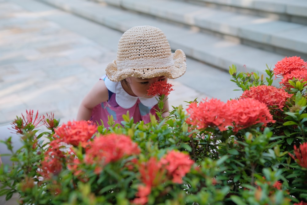 a little girl in a straw hat smelling flowers