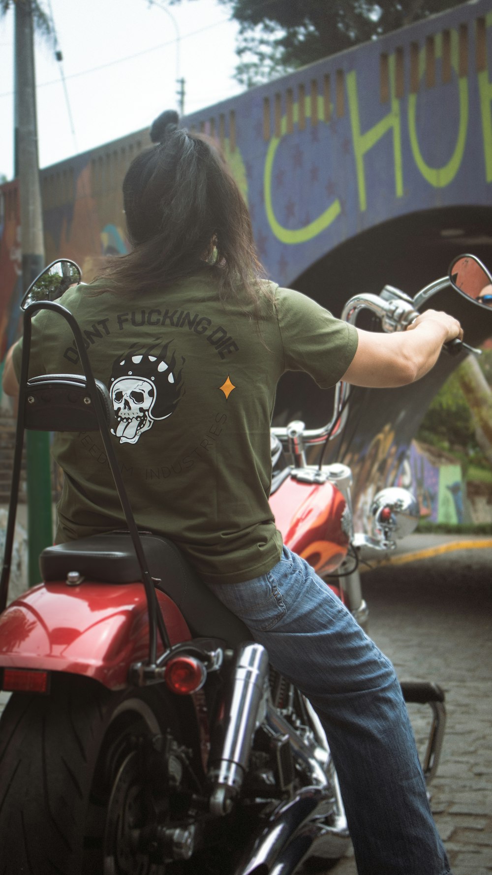 a woman sitting on a motorcycle in front of a bridge