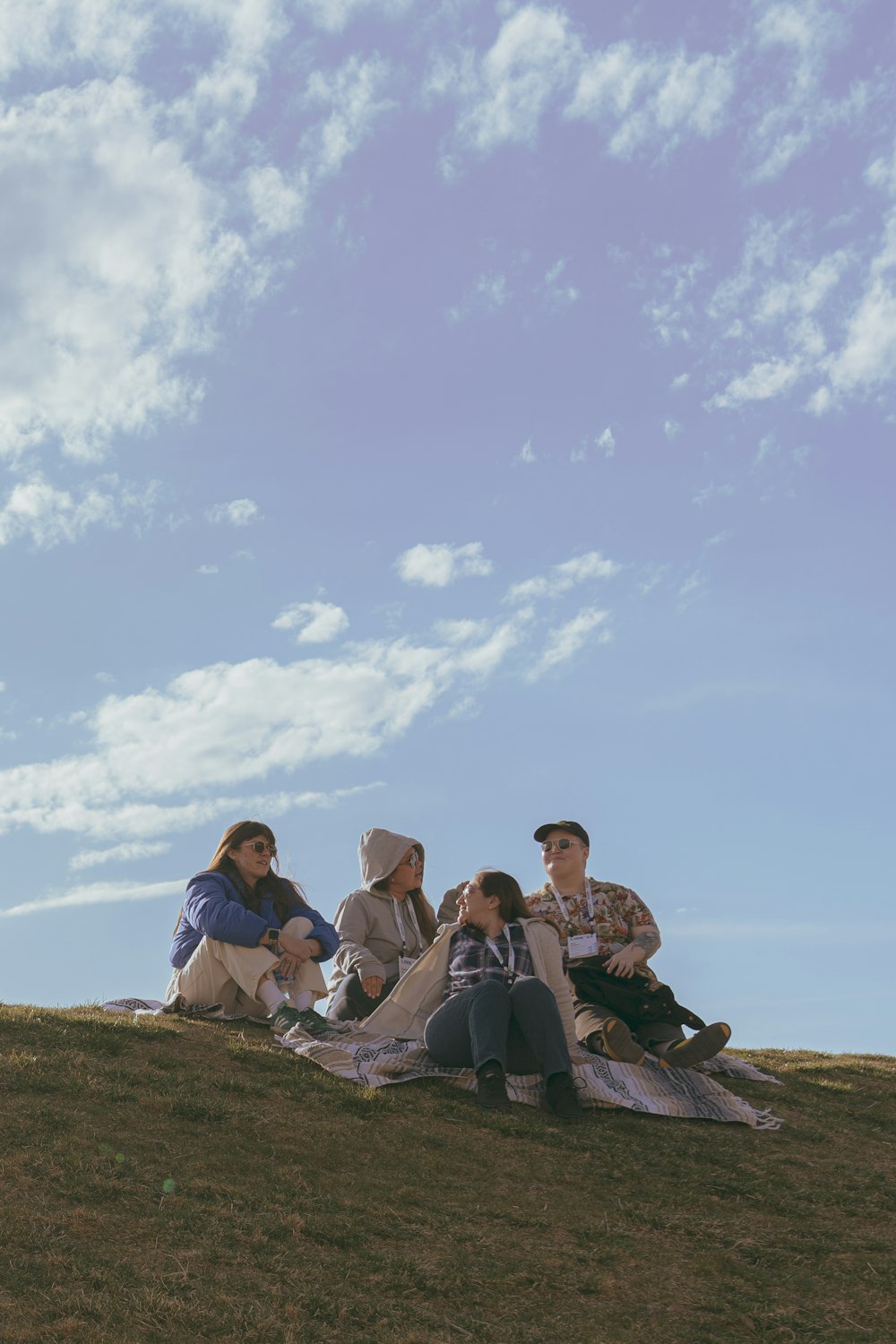 a group of people sitting on top of a grass covered hill