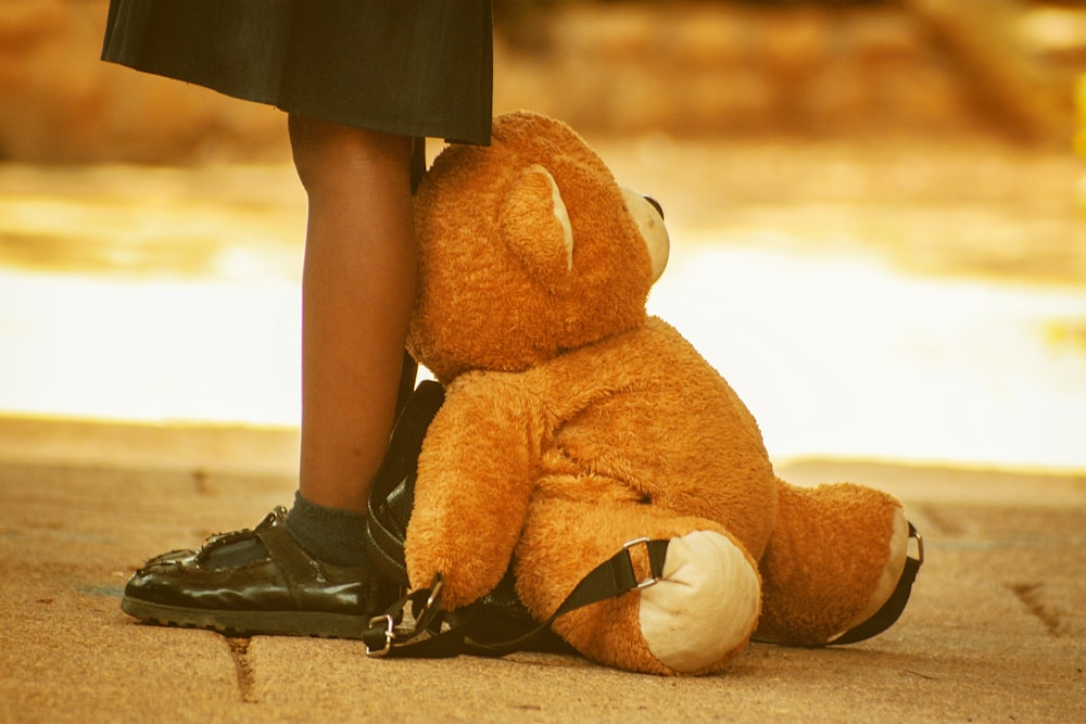 a brown teddy bear sitting on the ground
