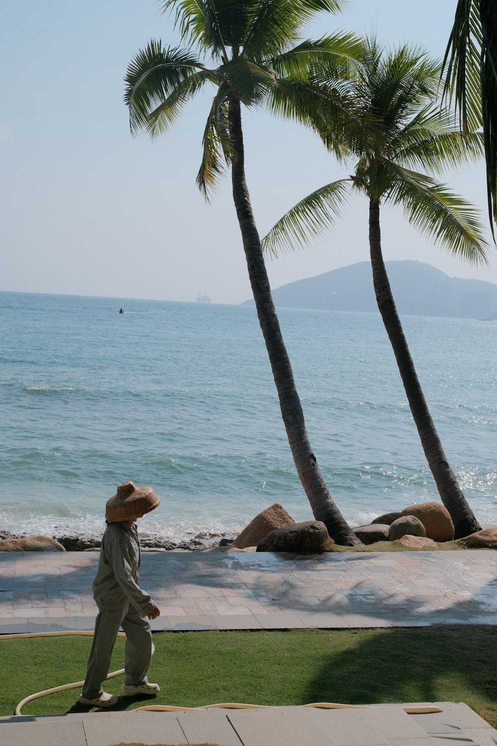 a man in a straw hat walks along the beach