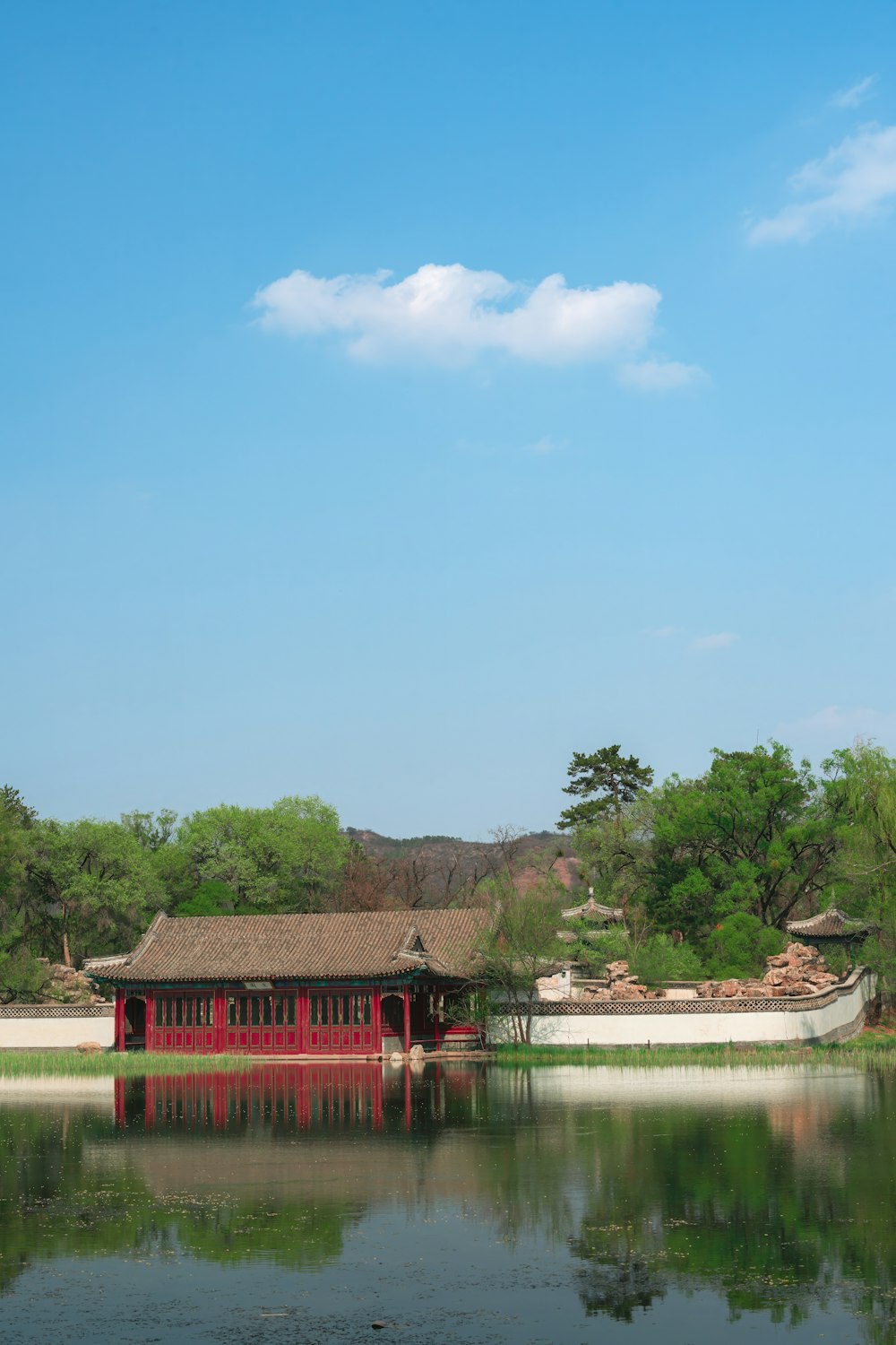 um edifício vermelho sentado no topo de um lago ao lado de uma floresta