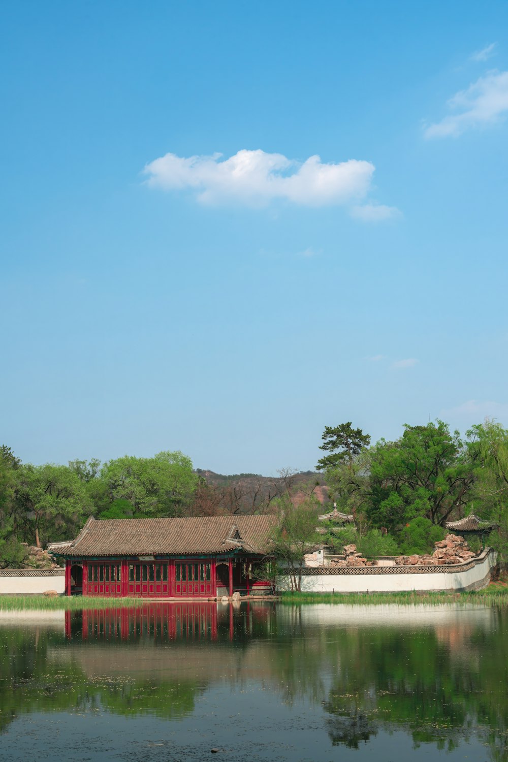 a red building sitting on top of a lake next to a forest