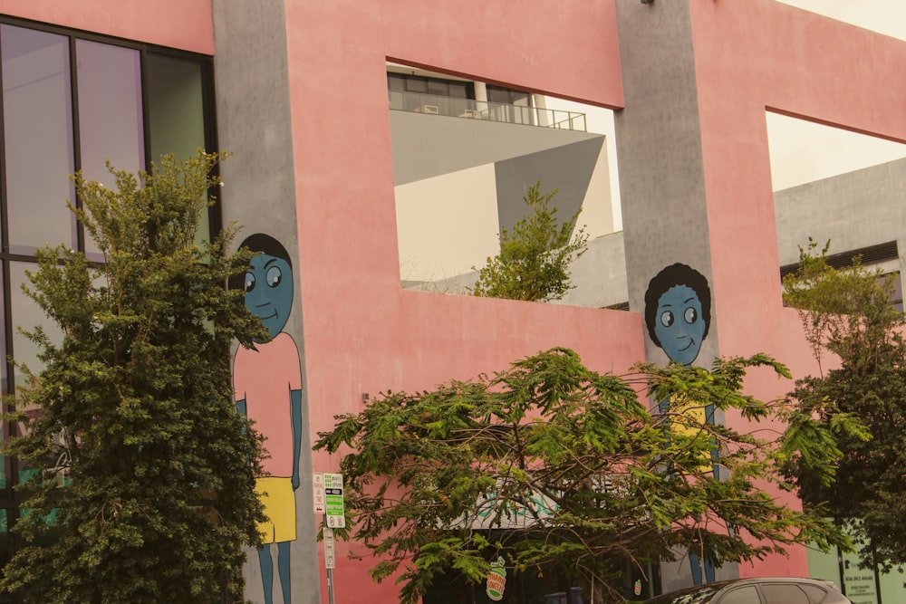 a pink building with two blue faces on it