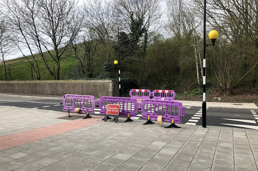 a group of purple benches sitting on the side of a road