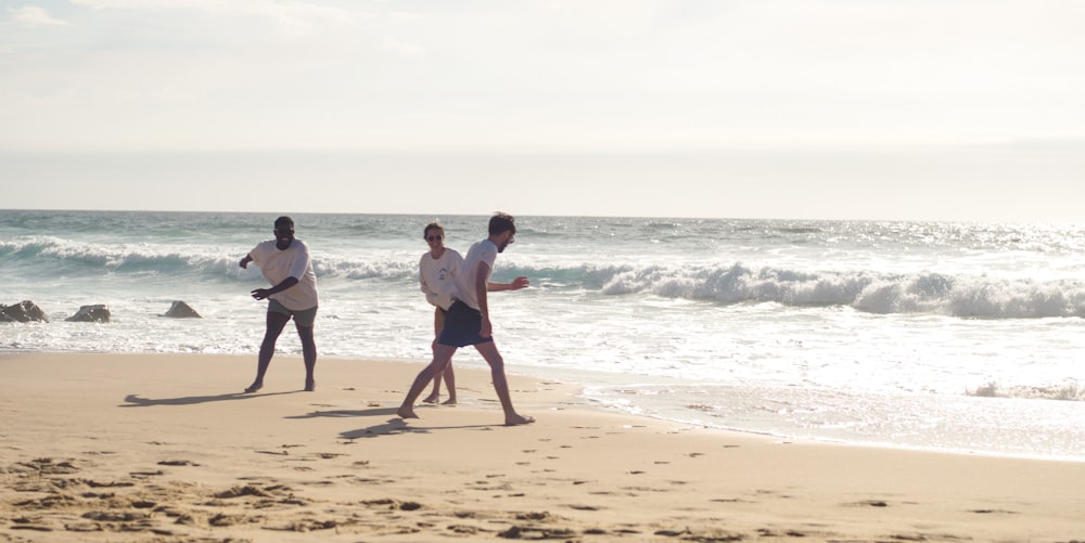 a group of people walking along a beach next to the ocean