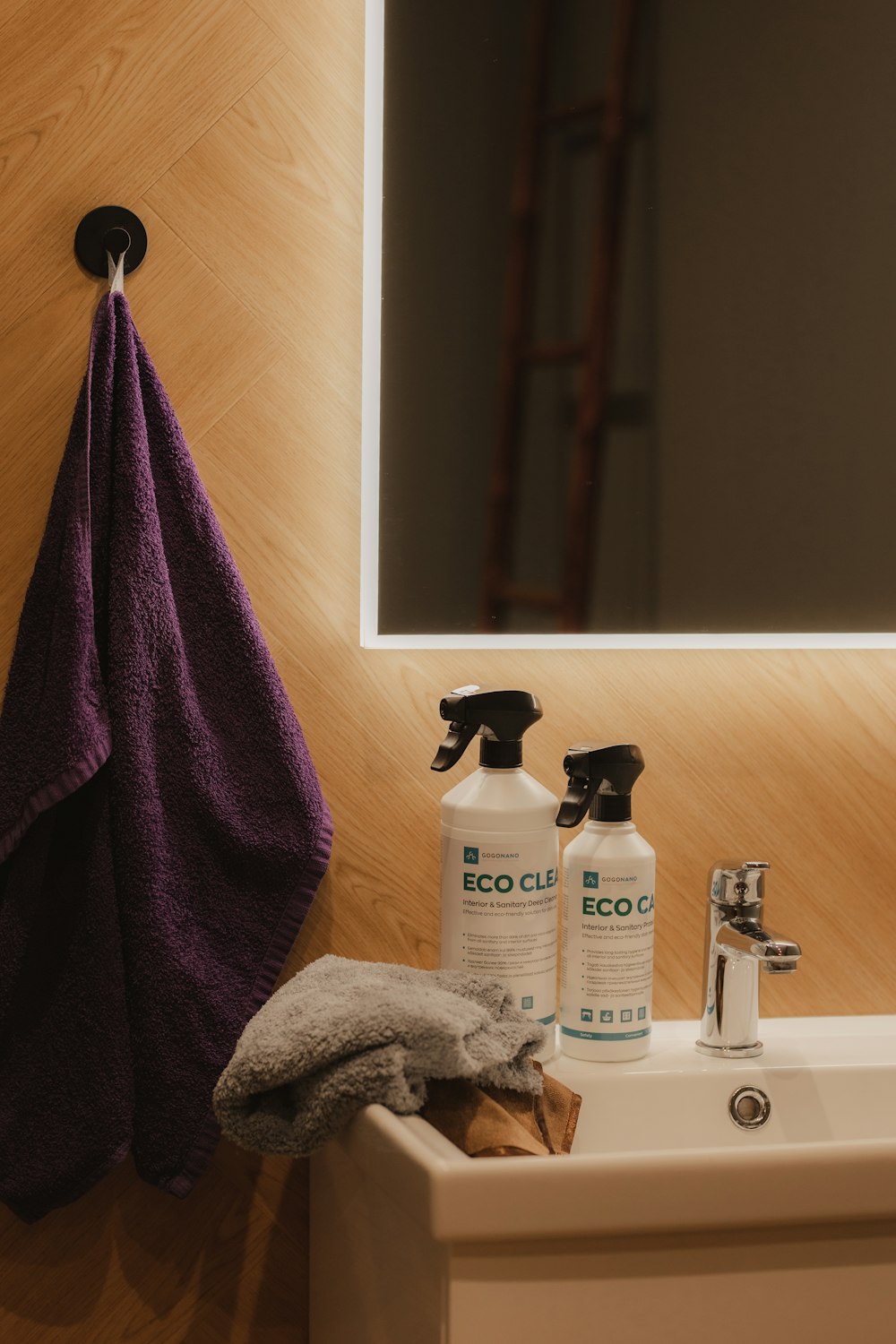 a bathroom sink with a purple towel hanging on the wall