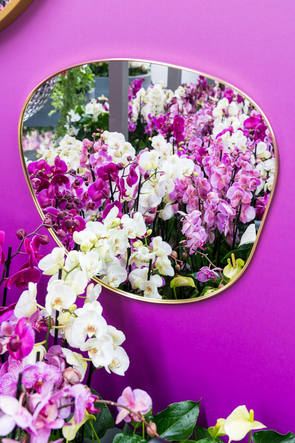 a mirror that is next to a bunch of flowers