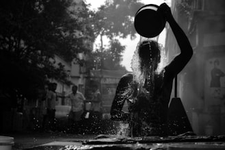 a woman standing in the rain with a bucket on her head
