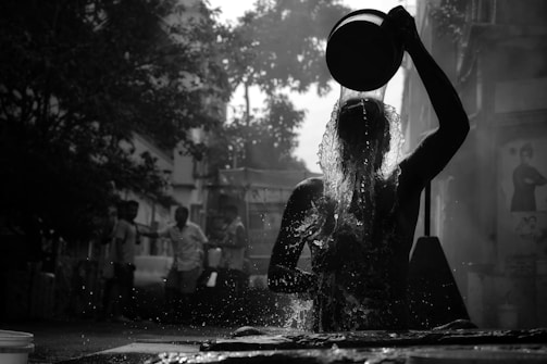 a woman standing in the rain with a bucket on her head