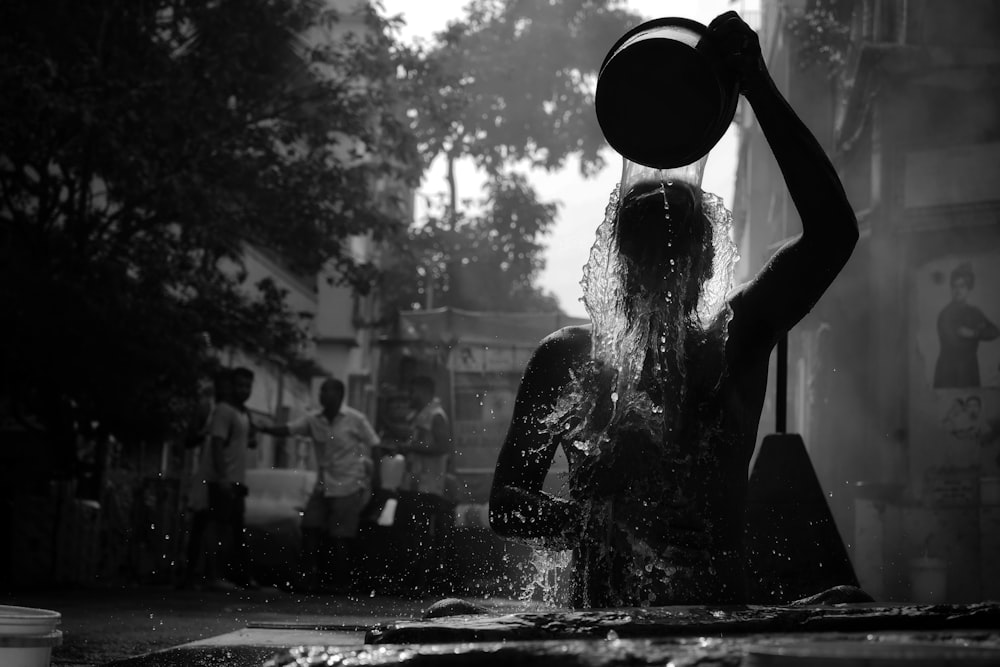 a woman standing in the rain with a bucket on her head