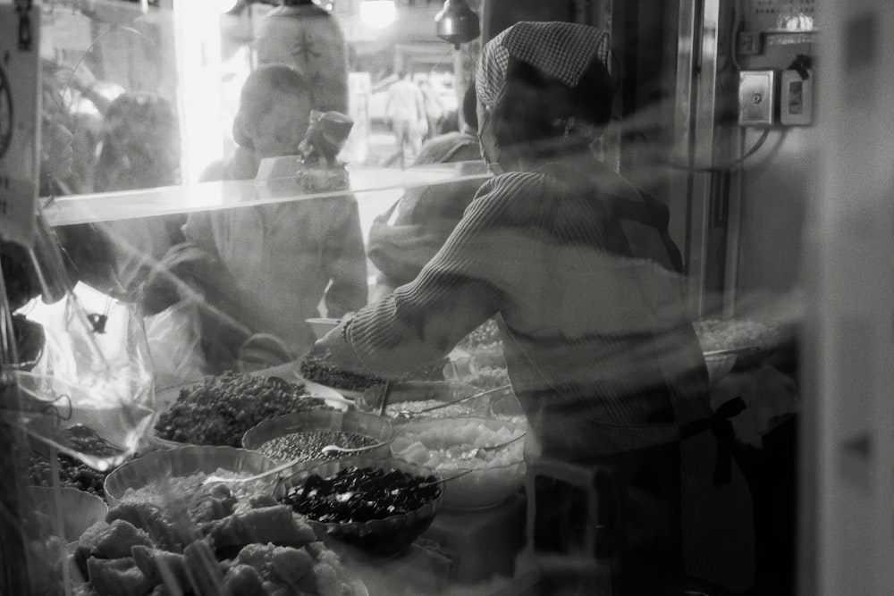 a woman standing behind a counter filled with food