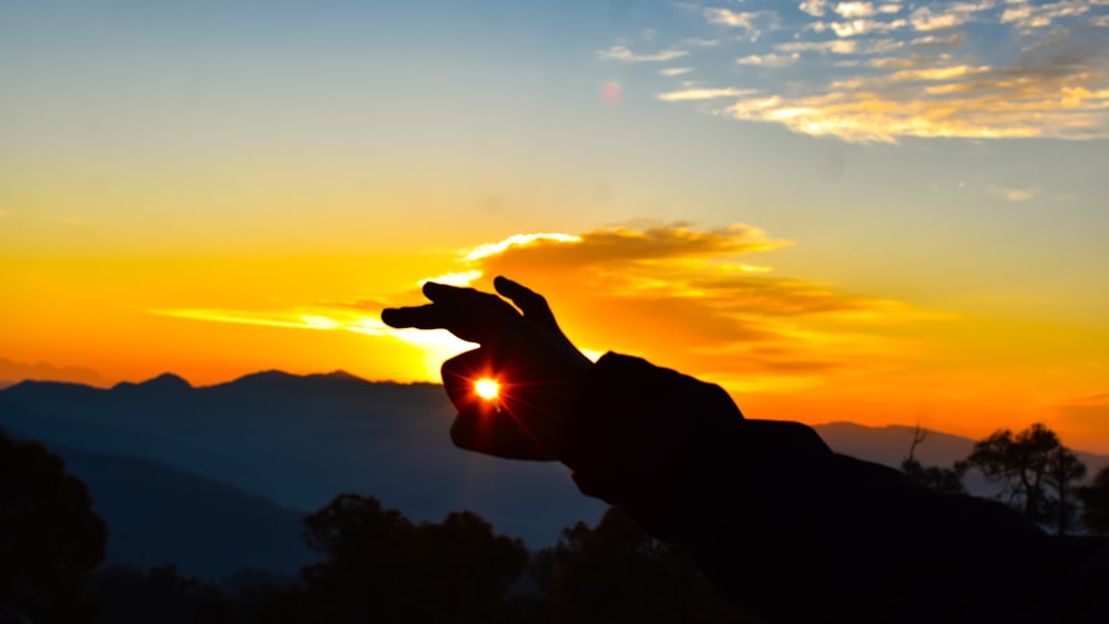 a person holding their hand up to the sun