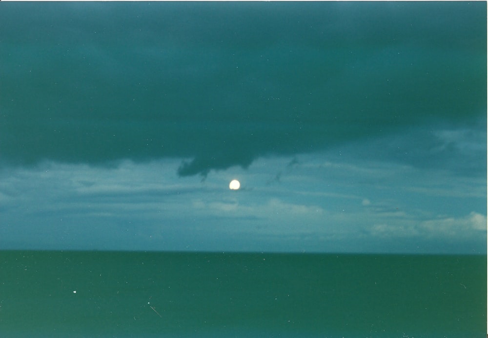 a full moon is seen in the distance over the ocean