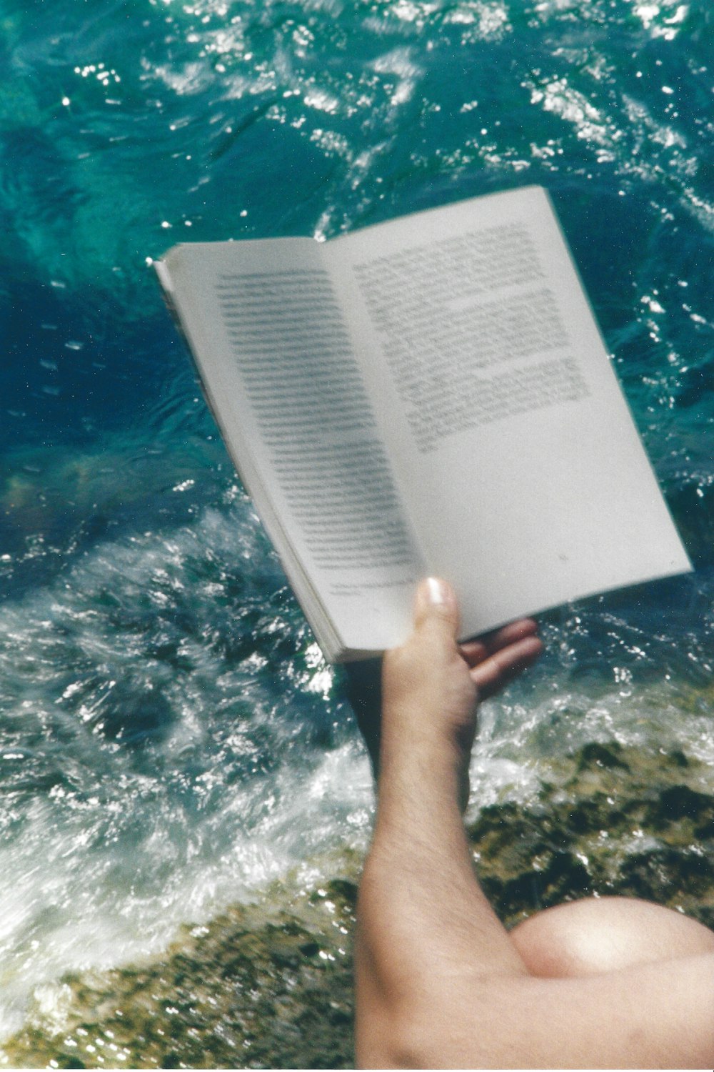 a person is reading a book by the ocean