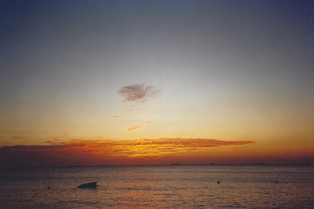 a sunset over a body of water with a boat in the distance