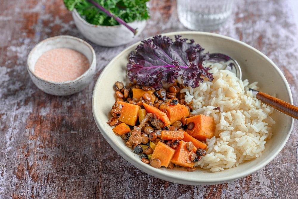 a bowl filled with rice and vegetables next to a bowl of sauce