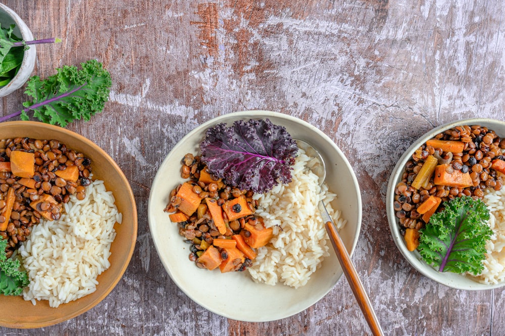 three bowls of food on a wooden table