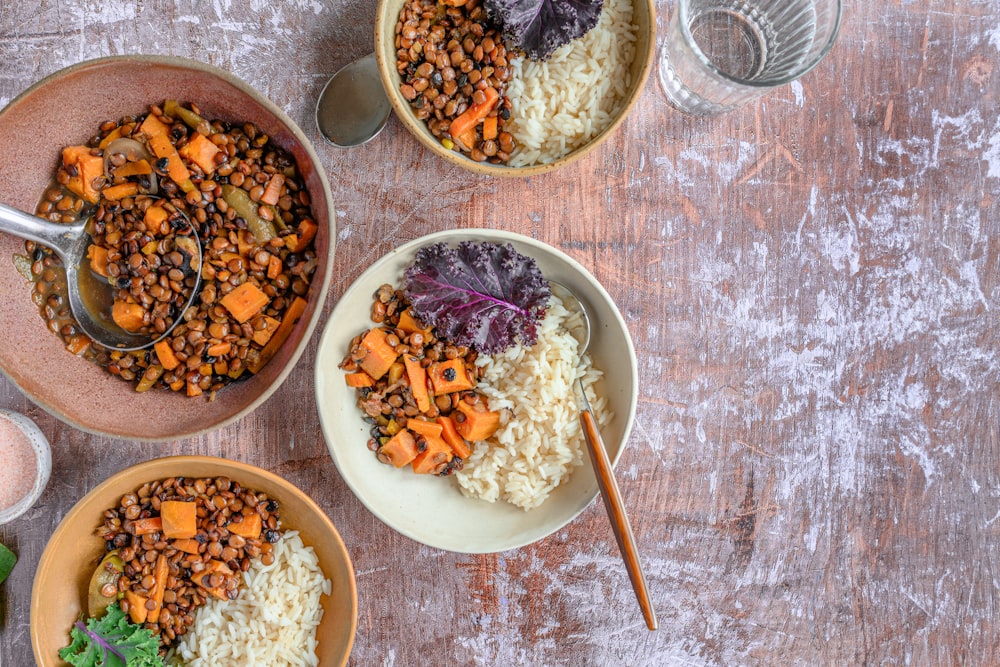 three bowls of food on a wooden table