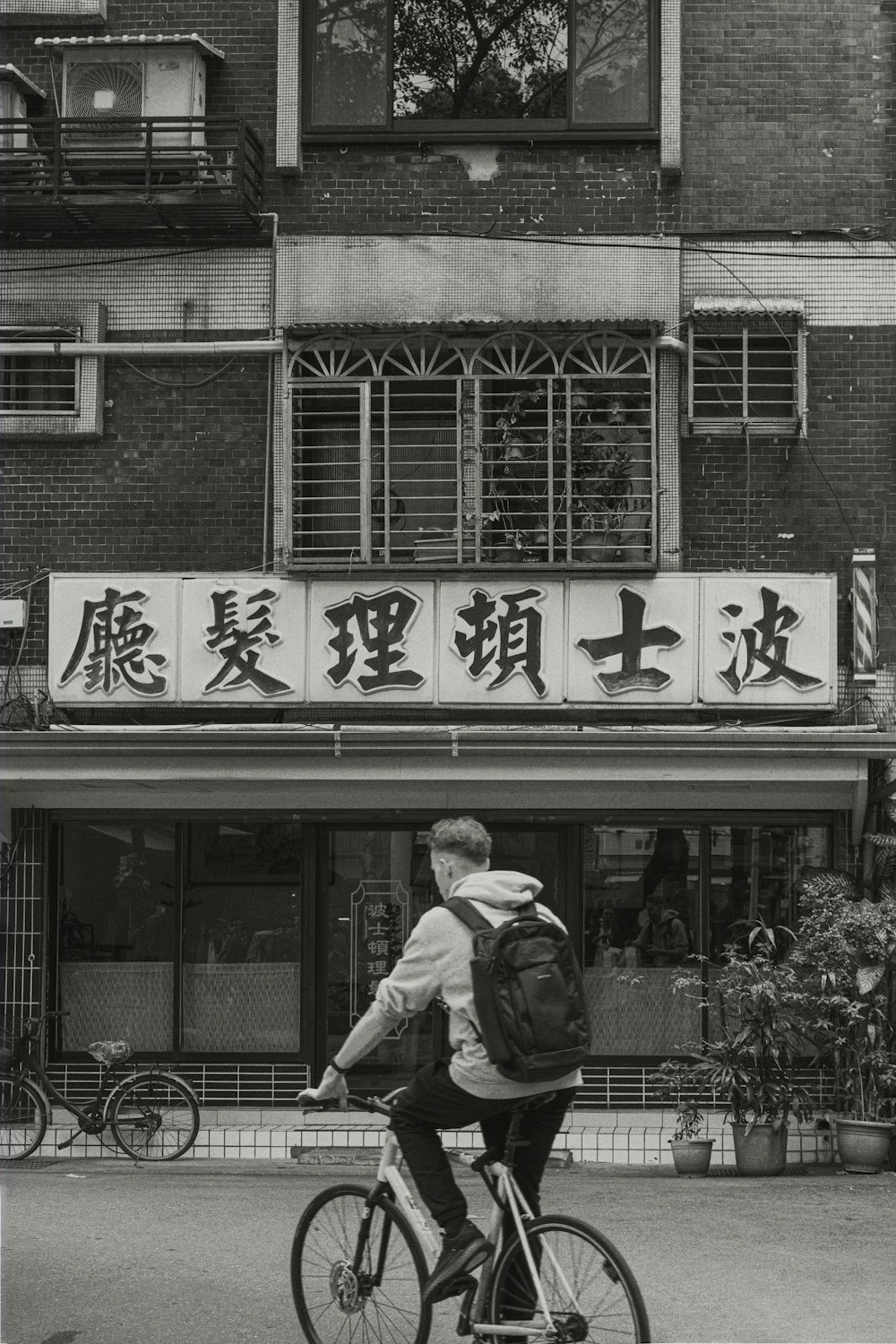 a man riding a bike down a street next to a tall building