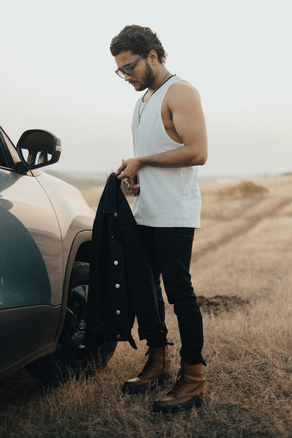 a man standing next to a car in a field