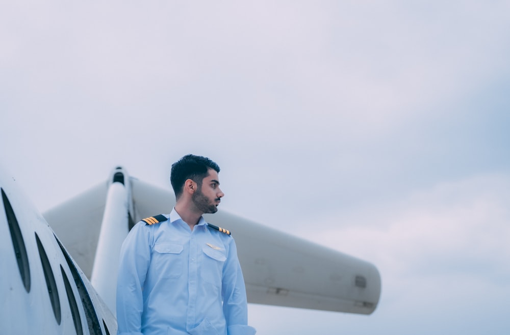 a man in uniform standing next to a plane