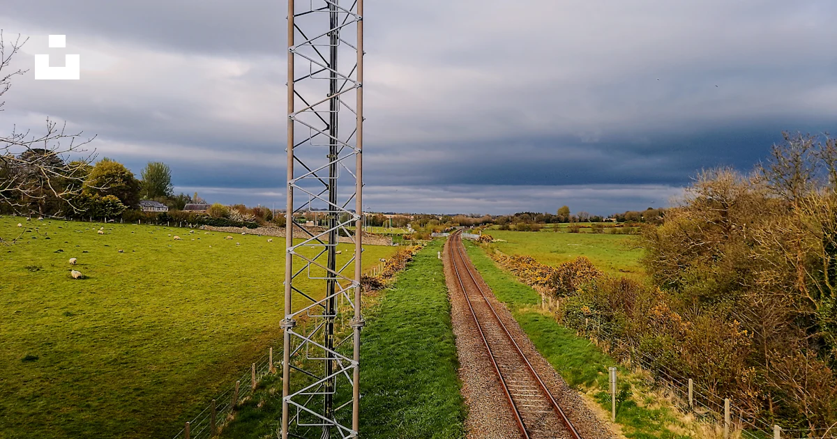 A train track running through a lush green field photo – Free Railway ...