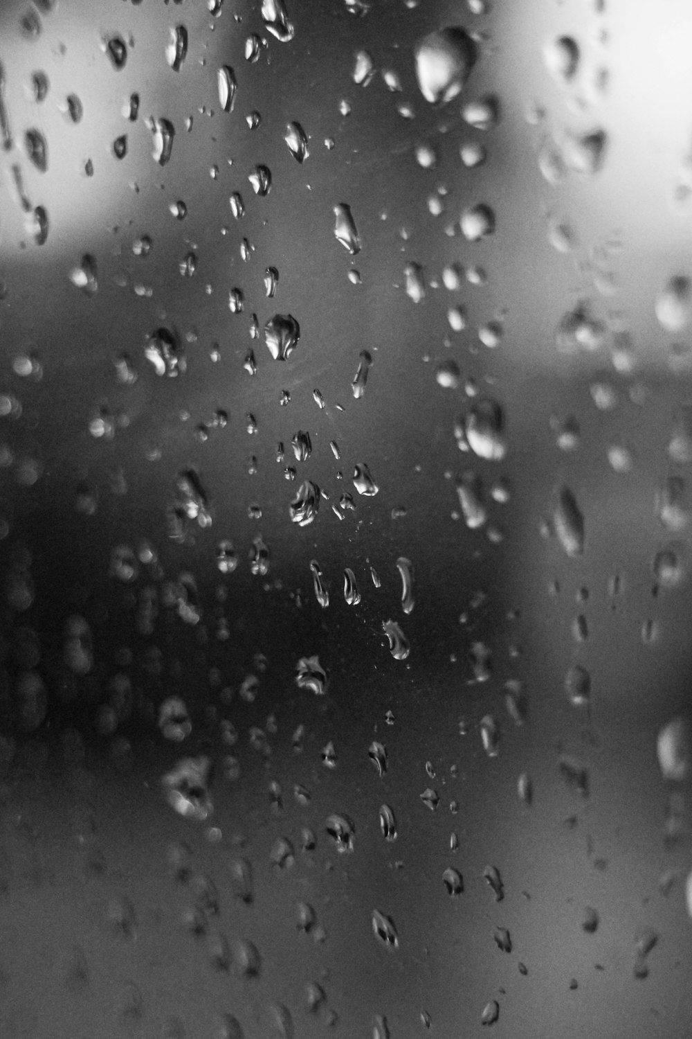 a black and white photo of rain drops on a window