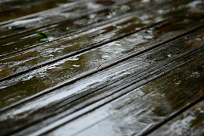 a close up of a wooden bench in the rain