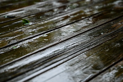a close up of a wooden bench in the rain