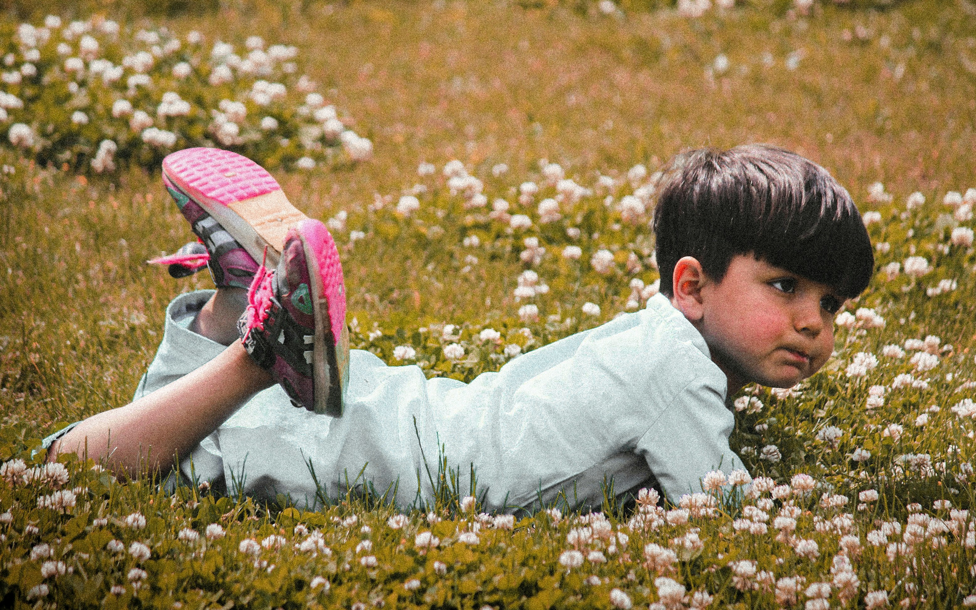 a young boy laying in a field of flowers