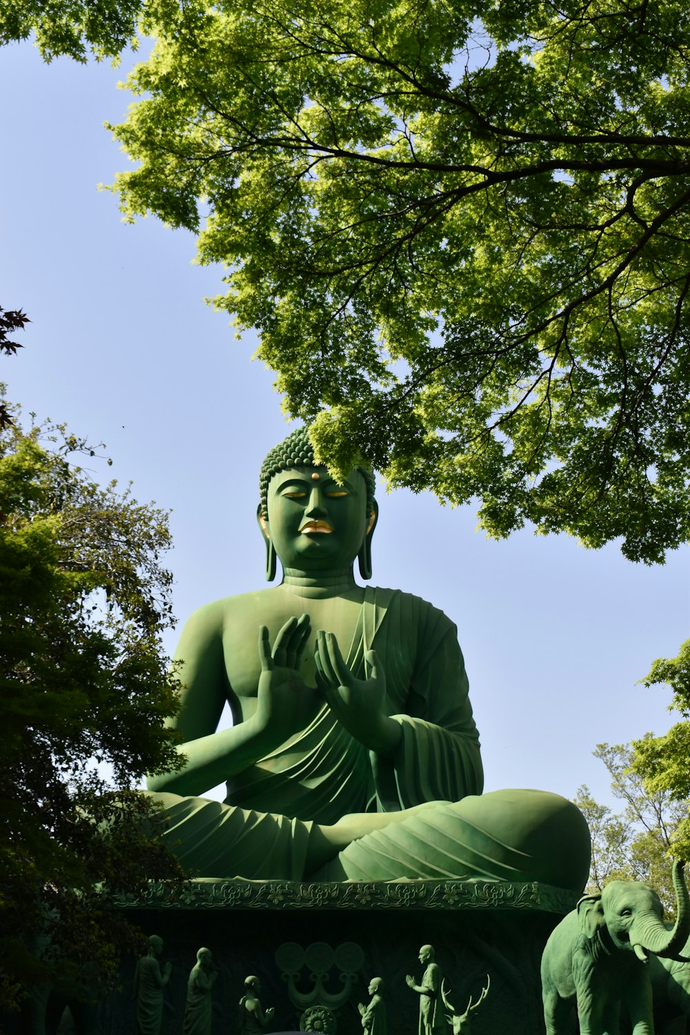 a statue of a buddha sitting in the middle of a park