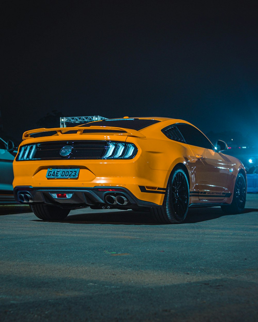 a yellow mustang parked in a parking lot at night