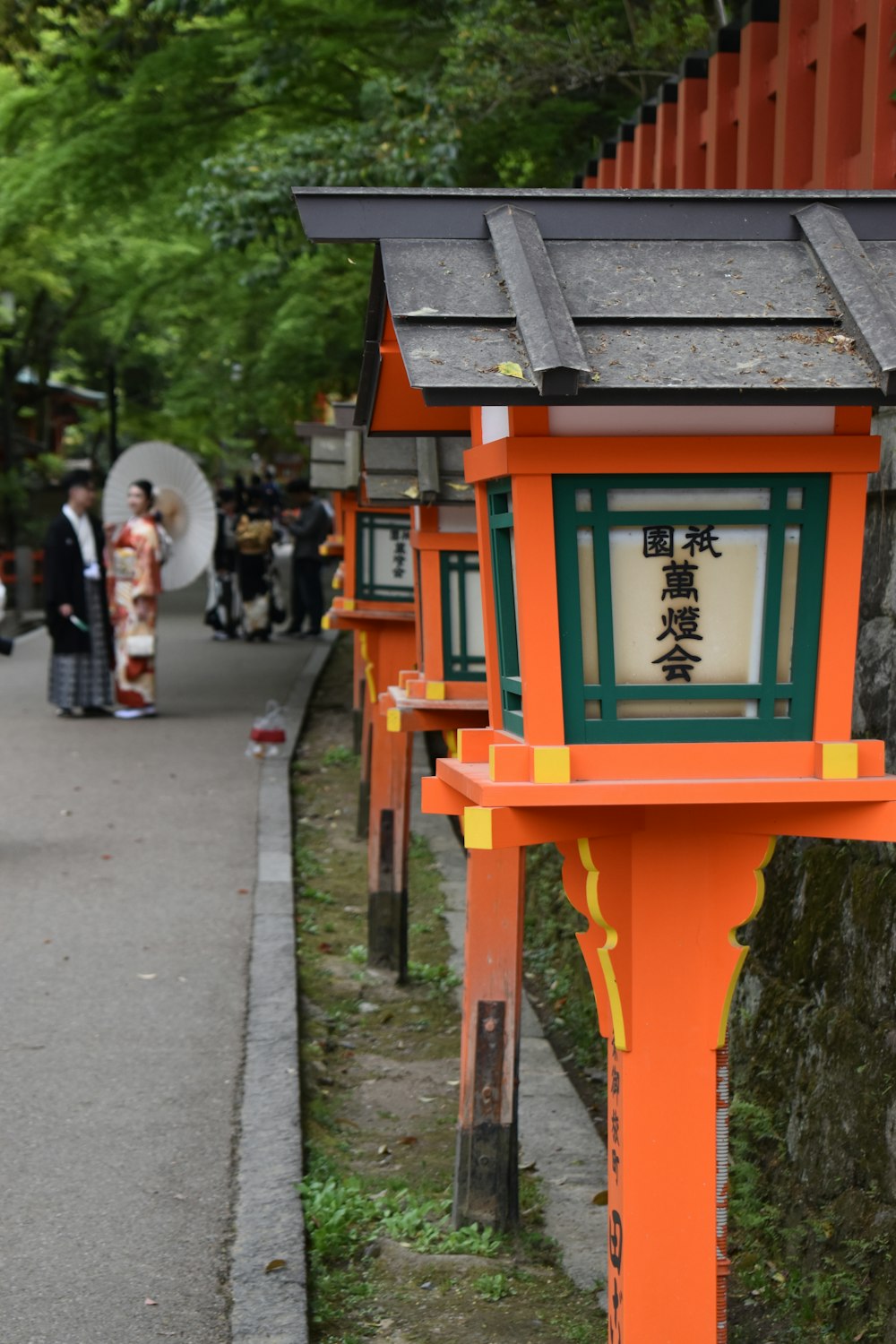 a row of orange and green lanterns on the side of a road