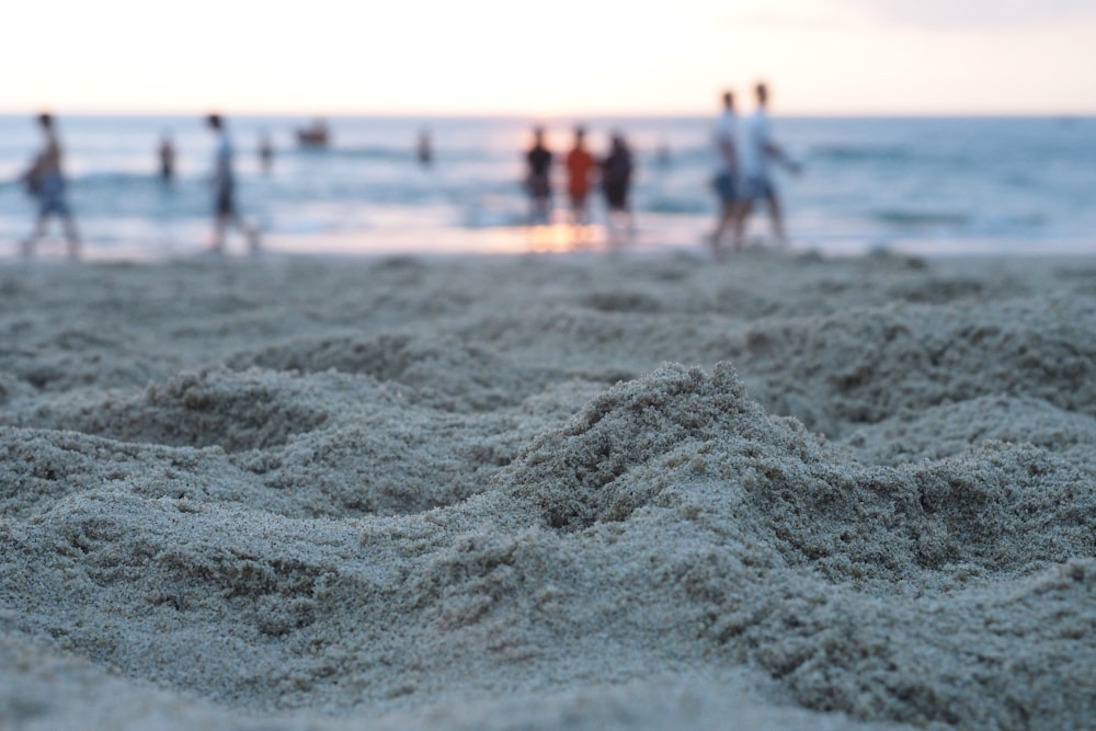 um grupo de pessoas em pé em cima de uma praia de areia