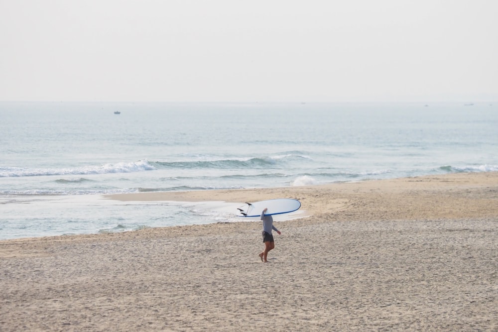 eine Person am Strand mit einem Surfbrett