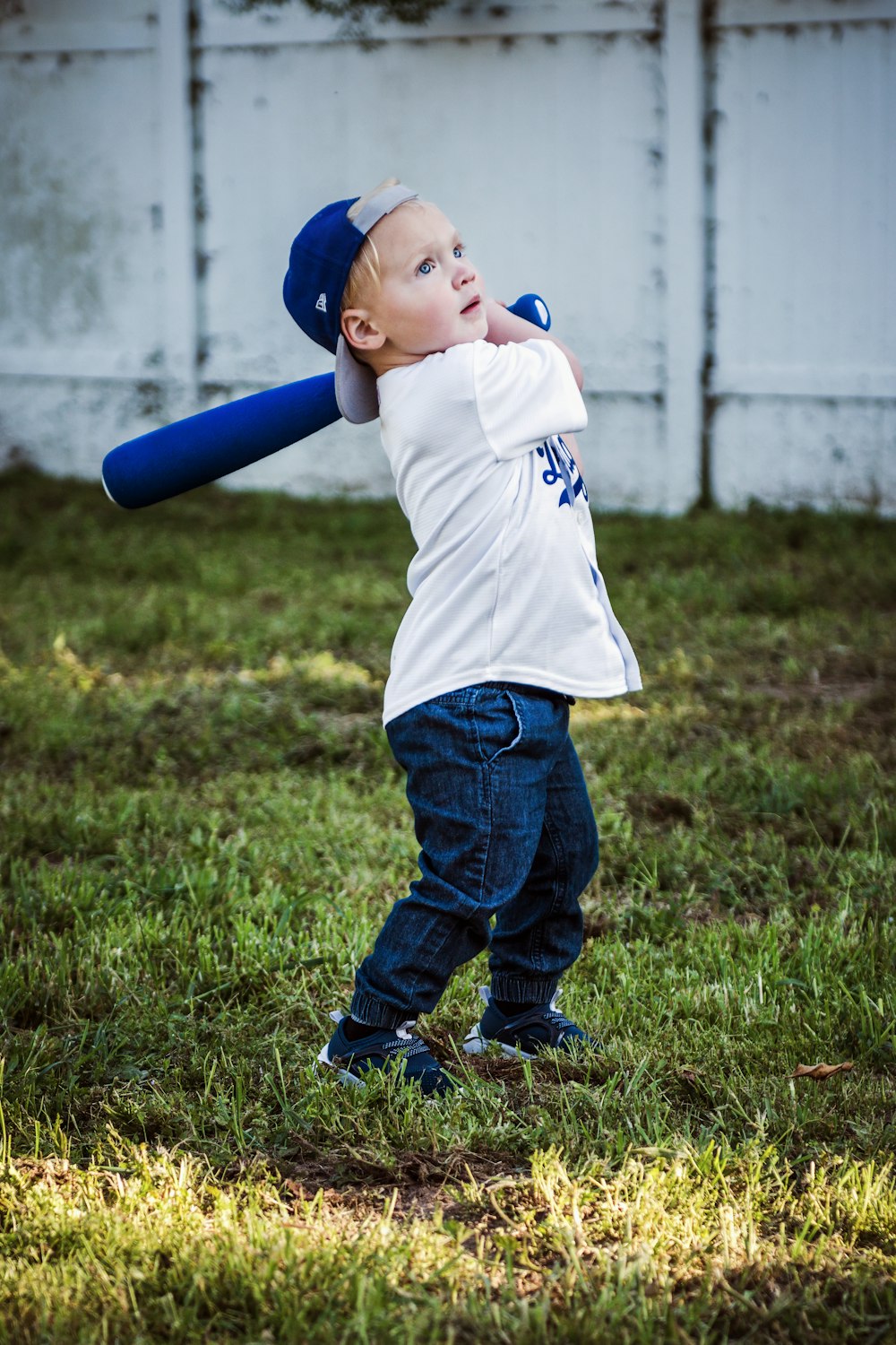 a young boy holding a baseball bat on top of a field