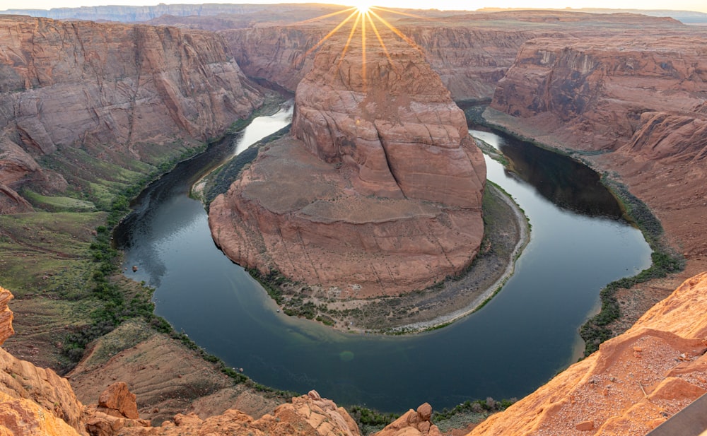 the sun is shining over a river in a canyon