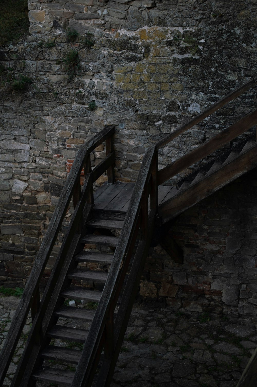 a wooden stair case next to a brick wall