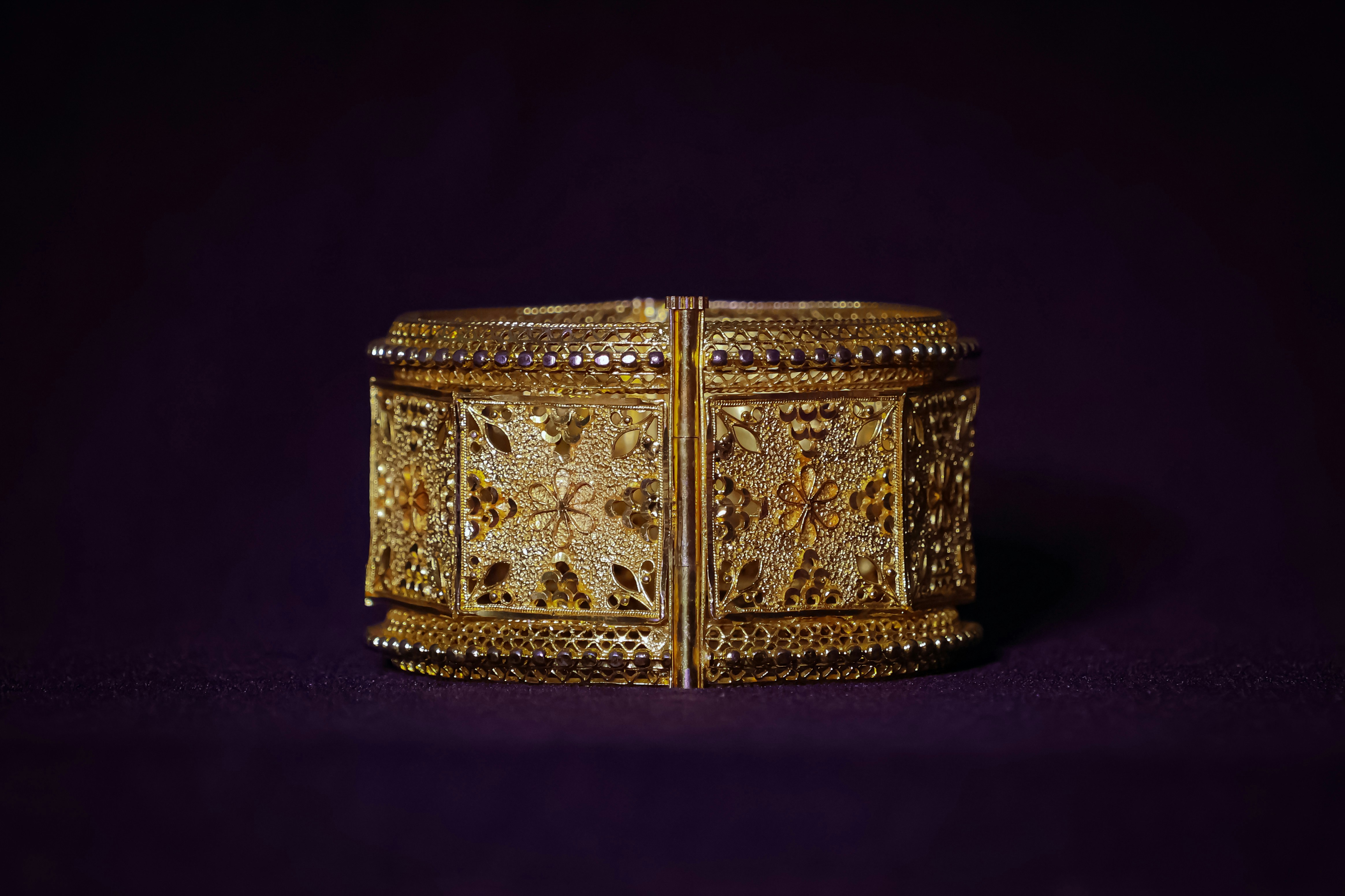 a gold bracelet is shown against a purple background