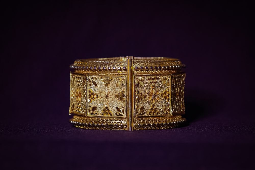 a gold bracelet is shown against a purple background
