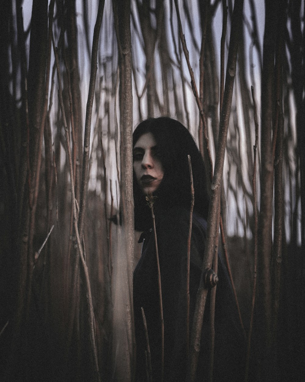 a woman in a hooded jacket standing in a forest