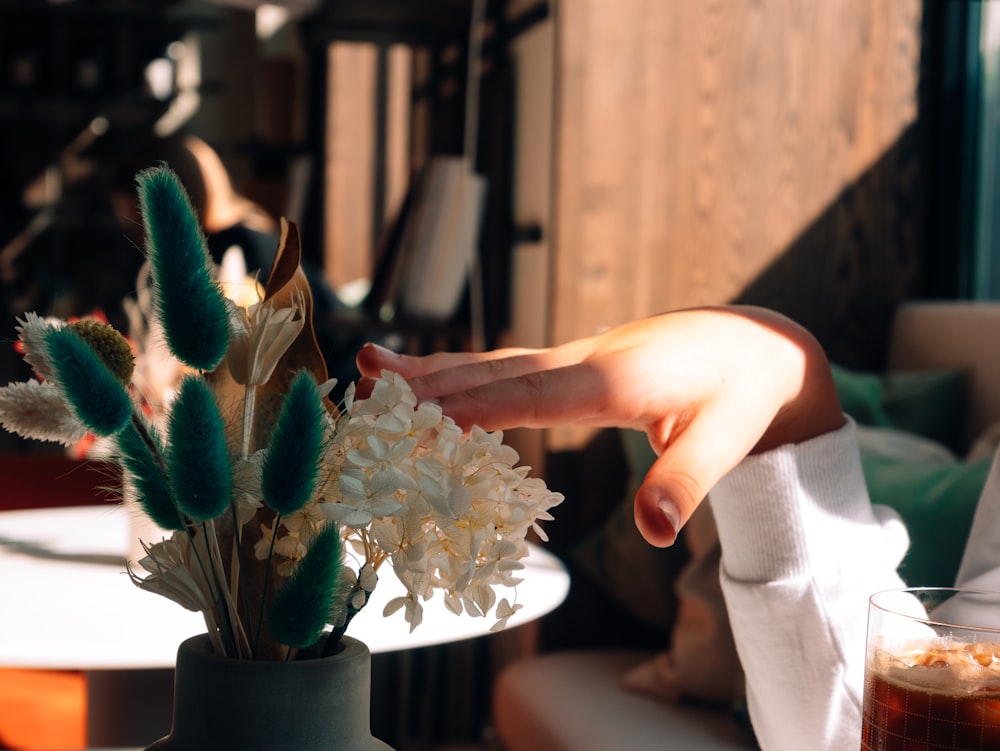 a person reaching for a flower in a vase