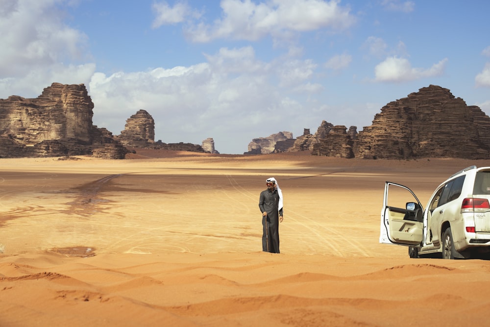 a man standing next to a car in the desert