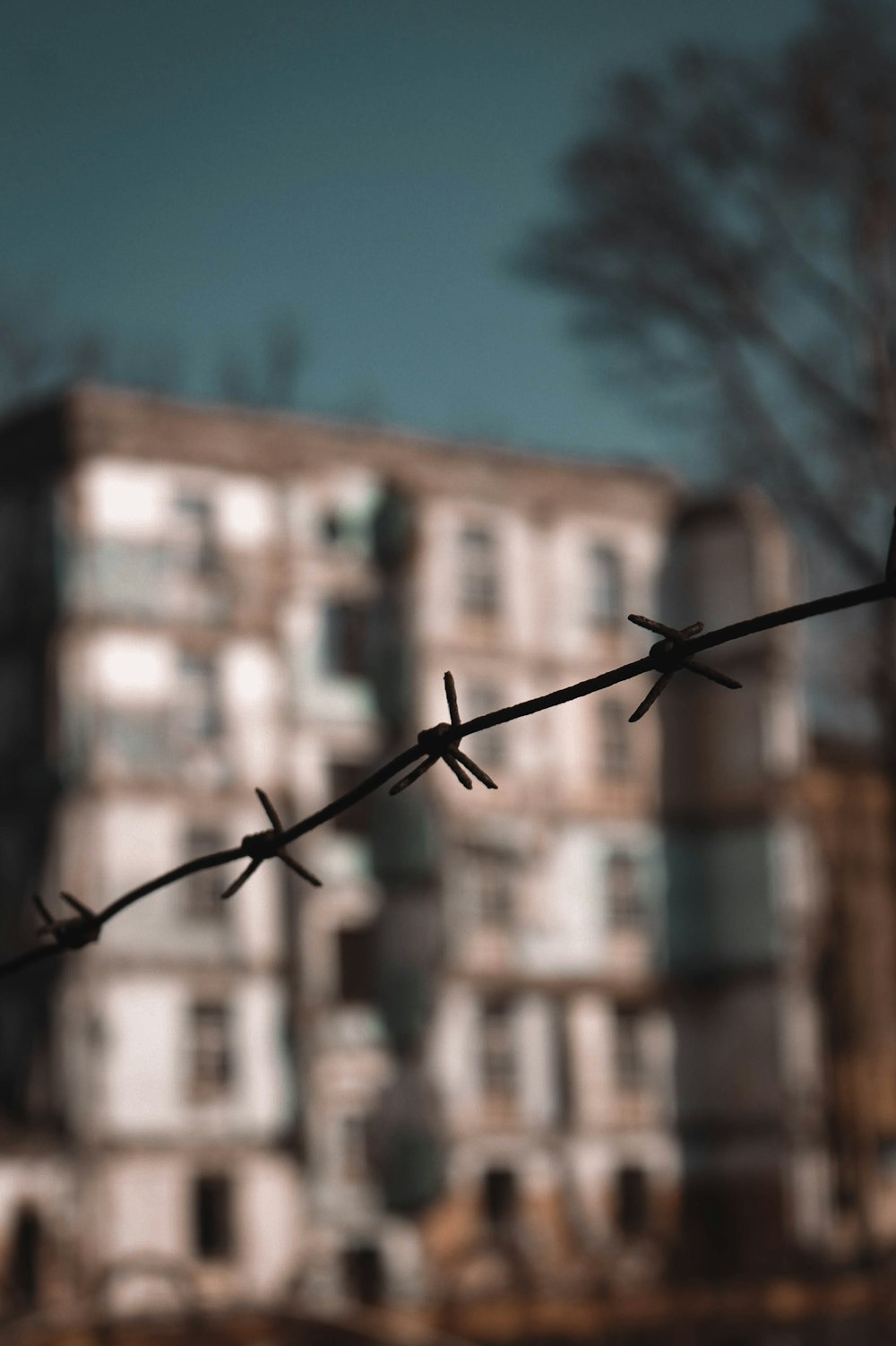 a close up of a barbed wire with a building in the background