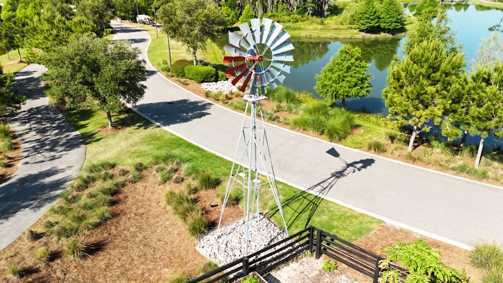 a windmill on the side of a road next to a lake