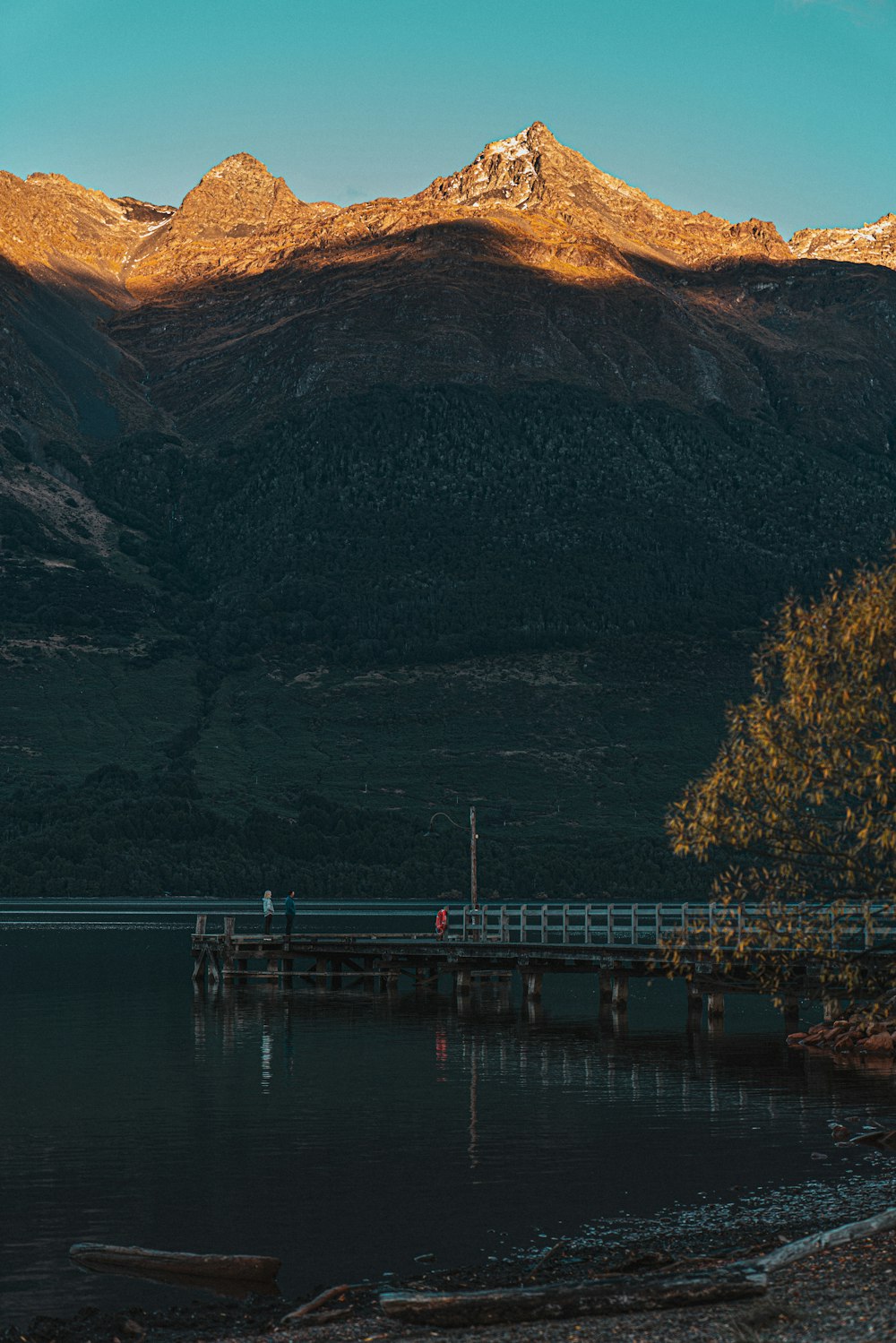 a couple of people standing on a pier next to a body of water