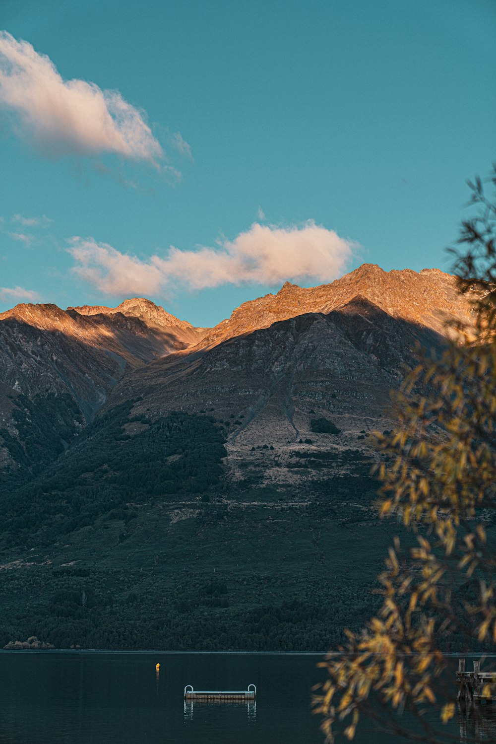 a lake surrounded by mountains under a blue sky