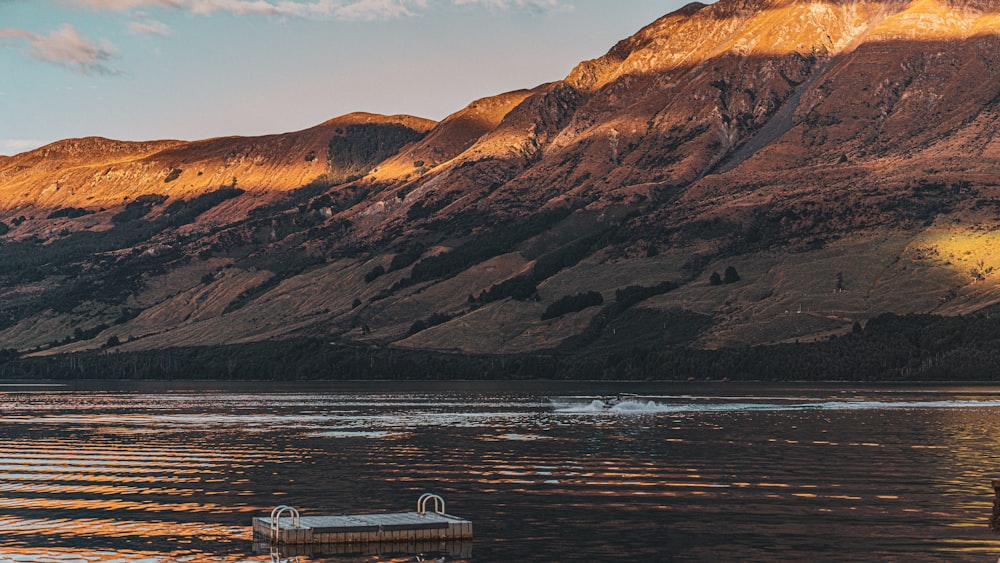 a boat floating on top of a lake surrounded by mountains